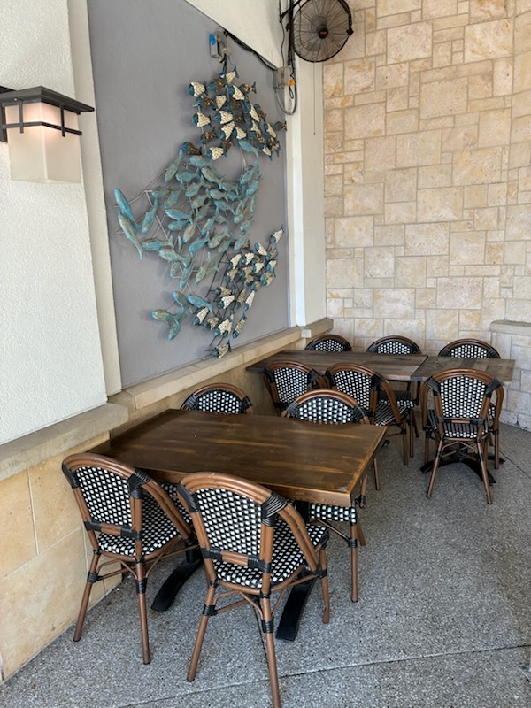 Patio tables beneath the fish sculpture wall at San Diego Grill